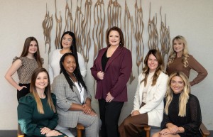 Group photo of the women-led team at Griffith Law Office, featuring eight team members seated and standing in a modern office space with an artistic wall sculpture in the background.